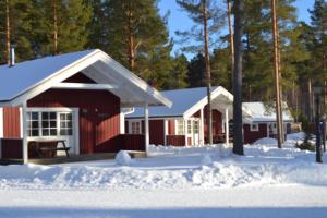 una casa roja con nieve delante en First Camp Enåbadet - Rättvik, en Rättvik