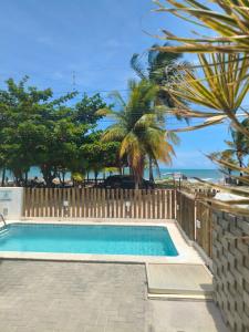 a swimming pool with a fence and a palm tree at Flat Beira-Mar Maragogi in Maragogi