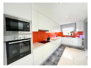 a kitchen with white cabinets and an orange wall at Villa Infinity Exclusive in Tías