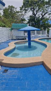 a small pool with a blue umbrella in the middle at HUBIBI Villa Staycation Balayan in Sepaco