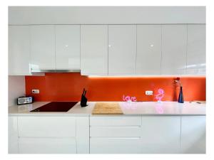 a kitchen with white cabinets and an orange wall at Villa Infinity Exclusive in Tías