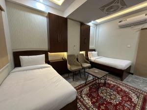a hotel room with two beds and a table at Hotel Araamish in Peshawar
