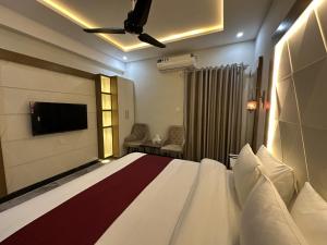 a hotel room with a bed and a flat screen tv at Hotel Araamish in Peshawar