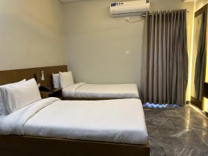 a hotel room with two beds and a window at Hotel Araamish in Peshawar