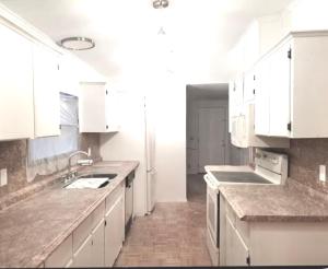 a white kitchen with white cabinets and a sink at Flossies in Seabrook +7 photos