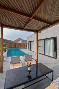 a patio with a glass table and a swimming pool at Kaizen Eirene Luxe Villas, Udaipur in Nāi