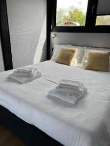 a white bed with towels on it with a window at Celesia SKy Water Andromeda in Sesto Calende