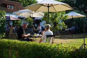 a man and woman sitting at a table under an umbrella at STF Vandrarhem Backåkra in Löderup +46 photos