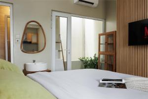a bedroom with a white bed and a mirror at Deva Bali Apartement in Kerobokan