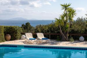 two chairs and a swimming pool with the ocean in the background at Villa KATHERINA G in Schinias
