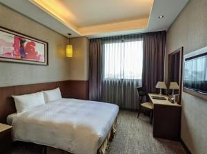a hotel room with a large bed and a desk at Guanko Hotel in Chiayi City