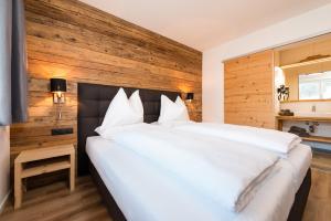 a bedroom with a large white bed with a wooden wall at APART Forellenhof in Flachau