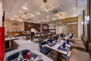 a restaurant with tables and chairs and a man standing in the middle at Lords Studio Inn, Jamnagar in Jamnagar