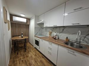 a kitchen with white cabinets and a sink and a table at Studio apartman Aria in Đakovo