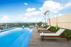 a pool on the roof of a building with lounge chairs at ARTOTEL Leguna Magelang in Magelang