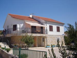 a white house with a balcony and a fence at Apartments Ada in Primošten