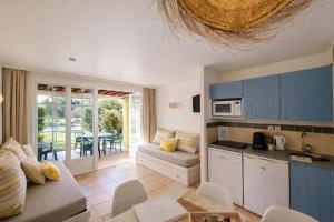 a kitchen and living room with blue cabinets and a table at Appartements au coeur du golf, proche du lac et vélodyssée in Biscarrosse