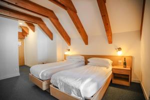 two beds in a room with wooden beams at Hotel Fortini in Madonna di Campiglio