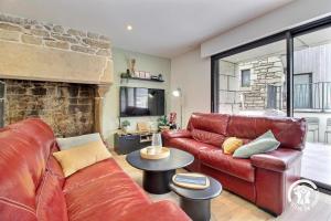 a living room with a red leather couch and a fireplace at Les maisons de l'if - le cottage in Pluméliau
