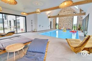 a swimming pool in a room with a couch and chairs at Les maisons de l'if - le cottage in Pluméliau