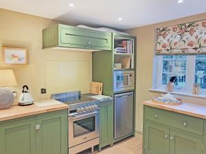 a kitchen with green cabinets and a stove top oven at Freshwater Barn in Benenden