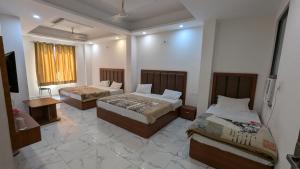 a room with two beds and a television in it at Hotel Kaushik Palace in Haridwār