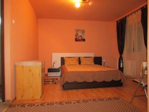 a bedroom with a bed with an orange wall at Central Accommodation Baile Felix in Baile Felix