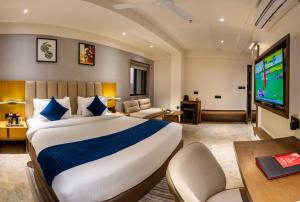 a hotel room with a large bed and a tv at Lords Studio Inn, Jamnagar in Jamnagar