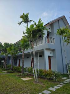 a building with palm trees in front of it at Luangwang Resort in Nai Yang Beach