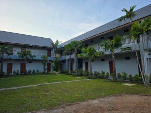 an exterior view of a building with palm trees at Luangwang Resort in Nai Yang Beach