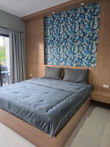 a bedroom with a large bed with a painting on the wall at Luangwang Resort in Nai Yang Beach