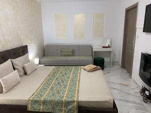 a bedroom with a large bed and a couch at Lemora Apartments 1 in Focşani +5 photos