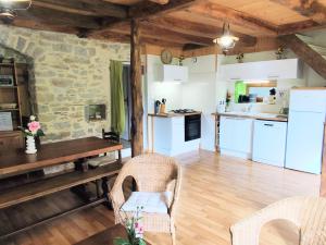 a kitchen with white appliances and a table and chairs at L'âne à plumes in Coisia