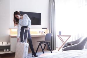 Hotel Stadt Balingen في بالينغن: امرأة تقف في غرفة في الفندق مع حقيبة
