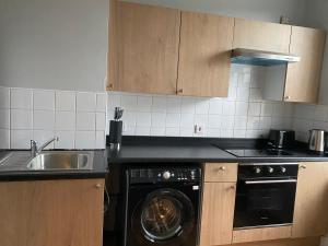 a kitchen with a black dishwasher and a sink at Baron Apartment B in Ballymena