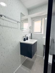 a white bathroom with a sink and a mirror at Velonia Guest House in Sozopol