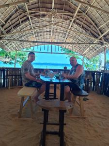 two men sitting at a table on the beach at Tress Maria's beach resort in Brother Islands