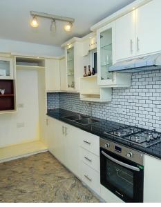 a kitchen with white cabinets and black counter tops at The Duchess Hotel in Matara