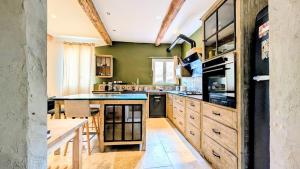 a kitchen with green walls and wooden cabinets at Caractère de Beaumes in Beaumes-de-Venise