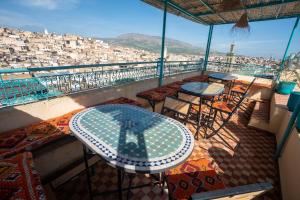 a balcony with tables and chairs and a view of a city at Dar Fayrouz in Fez
