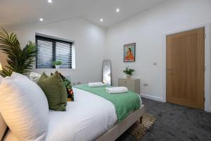 a bedroom with a large white bed with green pillows at The Knutsford loft in Knutsford