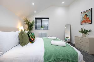 a bedroom with a large white bed with a green blanket at The Knutsford loft in Knutsford