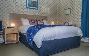 a bedroom with a large bed with a blue comforter at Hamilton House Guest House in Oban