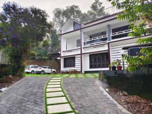 a house with a cobblestone road in front of it at Trinity Homestay Munnar in Anachal