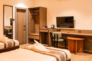 a hotel room with two beds and a desk with a television at The Hue House in Sibsāgar