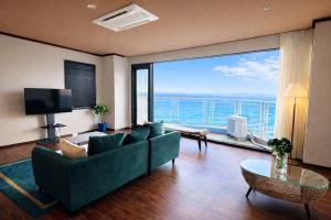 a living room with a green couch and a large window at 館山 New WestPeninsula Hotel ニューウエストペニンシュラホテル in Tateyama