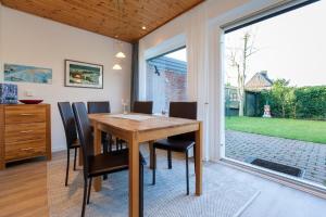 a dining room with a wooden table and chairs at Bungalow-Finlandia in Westerland +8 photos