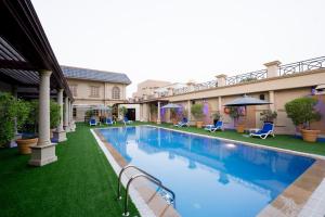 a swimming pool in the middle of a yard with chairs at Luxe Avenue Hotel in Dubai