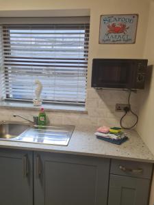 a kitchen counter with a sink and a tv at UlsterApartments one bedroom 2 single beds and sofa bed in Portrush +30 photos