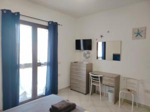 a bedroom with a desk and a dresser with a window at Bed & Breakfast Gli Alisei in Siniscola